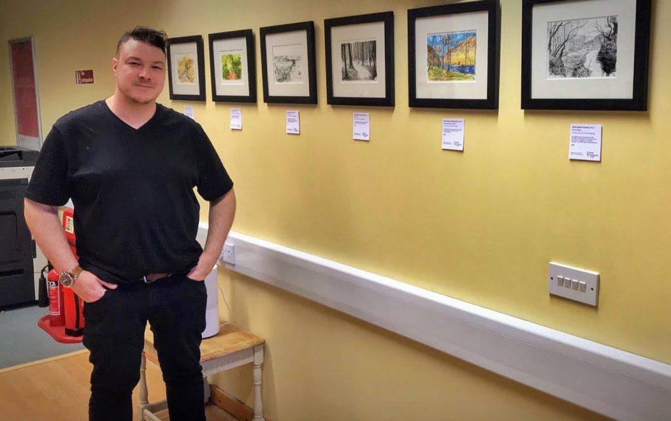 Artist Chris Richards standing in front of his framed artwork